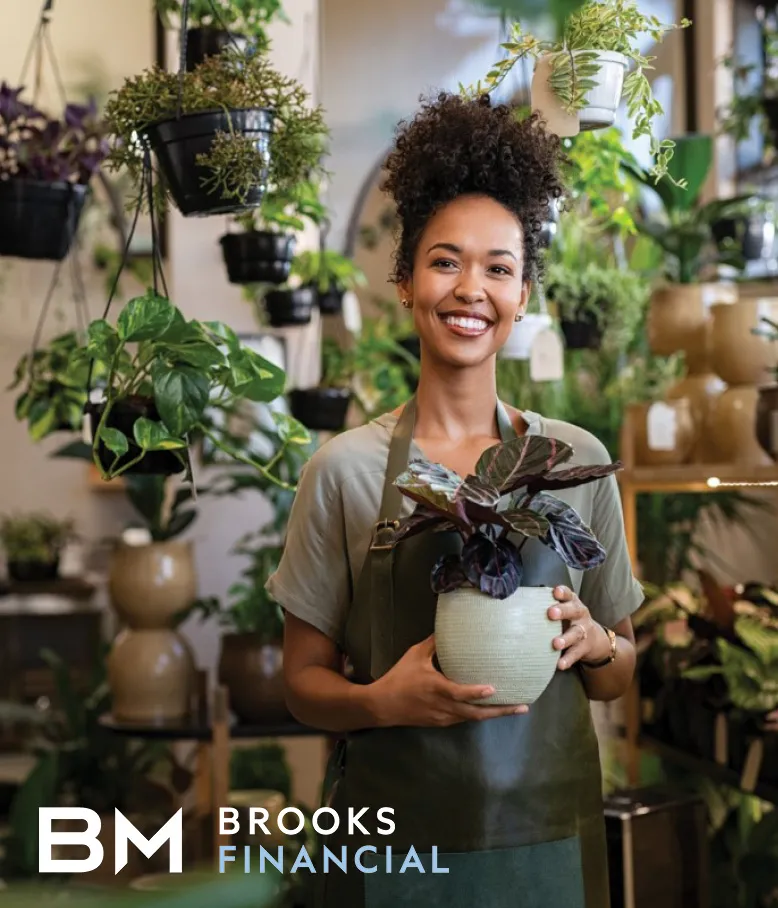 A woman standing in the plant shop holding a white plant pot