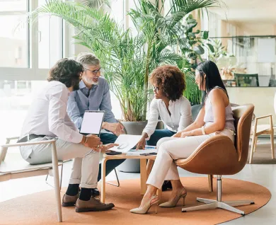 Four people sitting around a small table discussing graphs