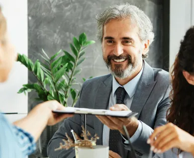A smiling man with a beard handing a clipboard to a woman
