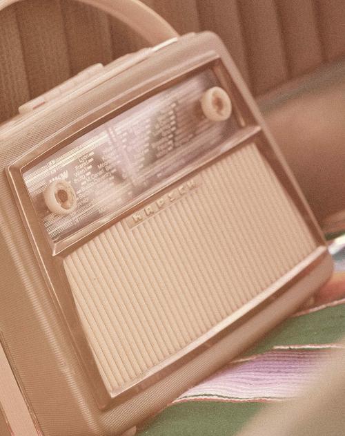 A vintage radio sits on the back seat of a vintage car
