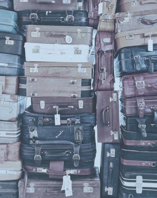 Dozens of vintage suitcases are stacked on top of each other and side by side