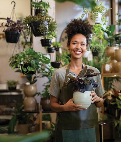 A woman standing in the plant shop holding a white plant pot