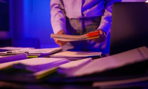 a person looking at piles of documents on a table