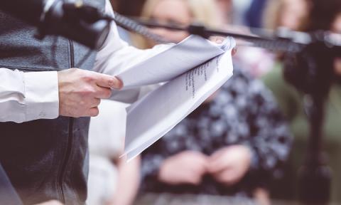 man reading a press release to a group of media