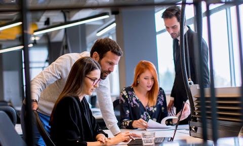 A group of four office workers working around a table
